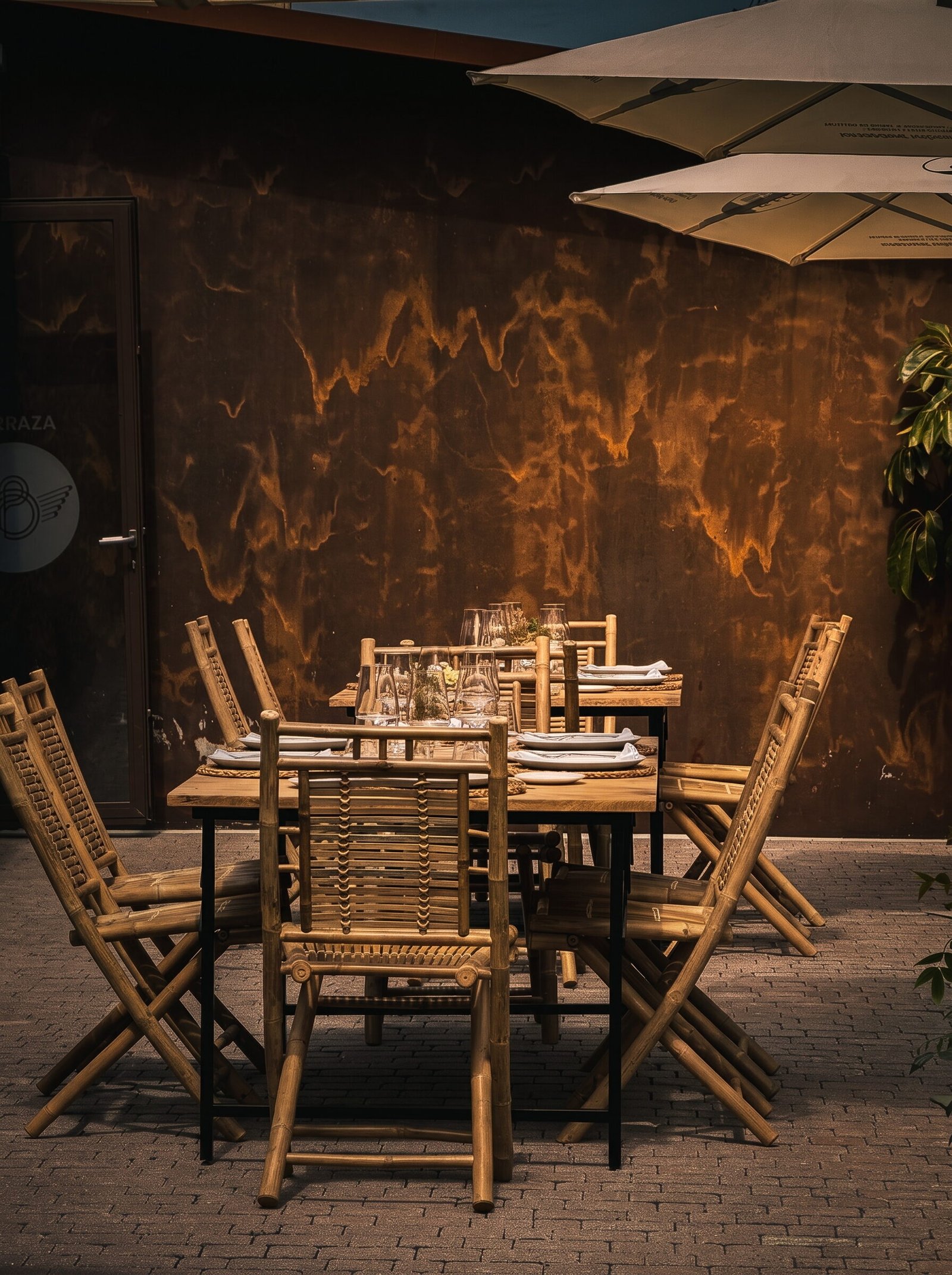 Mesas de madera en la terraza, frente al muro de acero corten